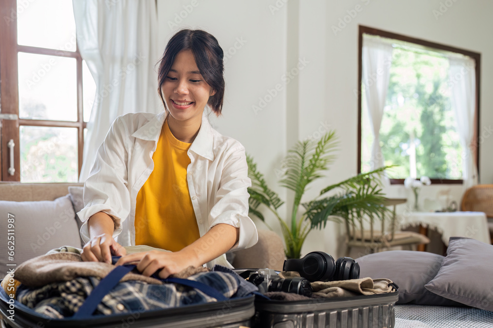 Young woman sit in floor and preparation suitcase for travelling at weekend trip