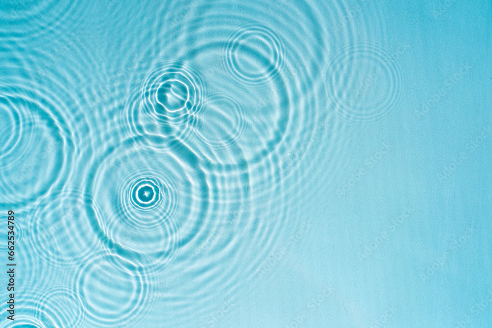 Raindrops on the surface of the water. Swimming pool water background with drops and ripples from rain. Abstract natural backdrop