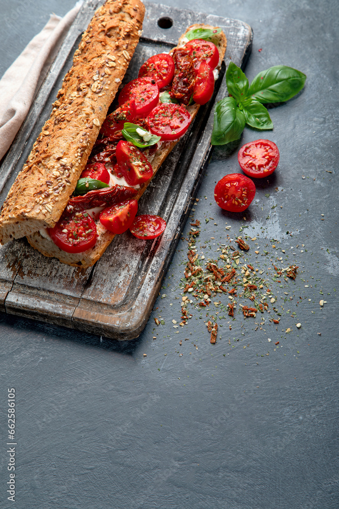 Fresh baguette with Caprese. Delicious sandwich with with tomatoes and mozzarella cheese with fresh basil leaves. Italian food conception.