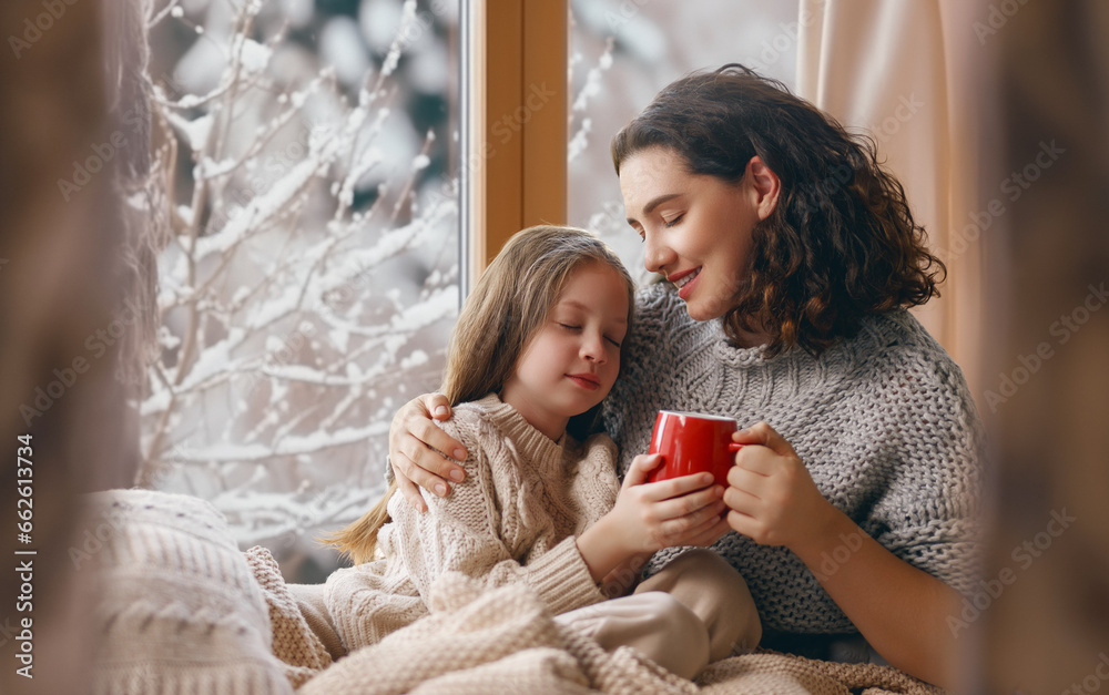 Mother and daughter enjoying winter nature in the  window