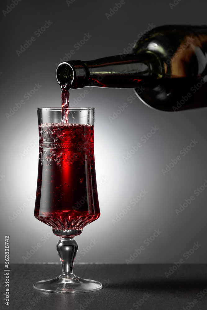 Dessert wine or liqueur is poured into a glass from an ancient bottle.