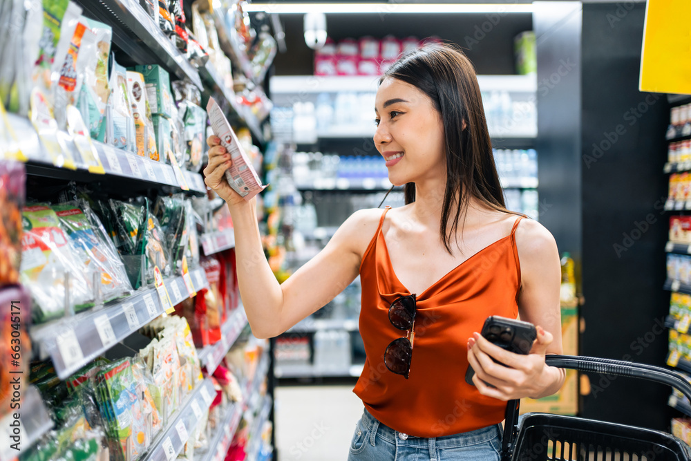 Asian young beautiful woman holding grocery basket walk in supermarket. 