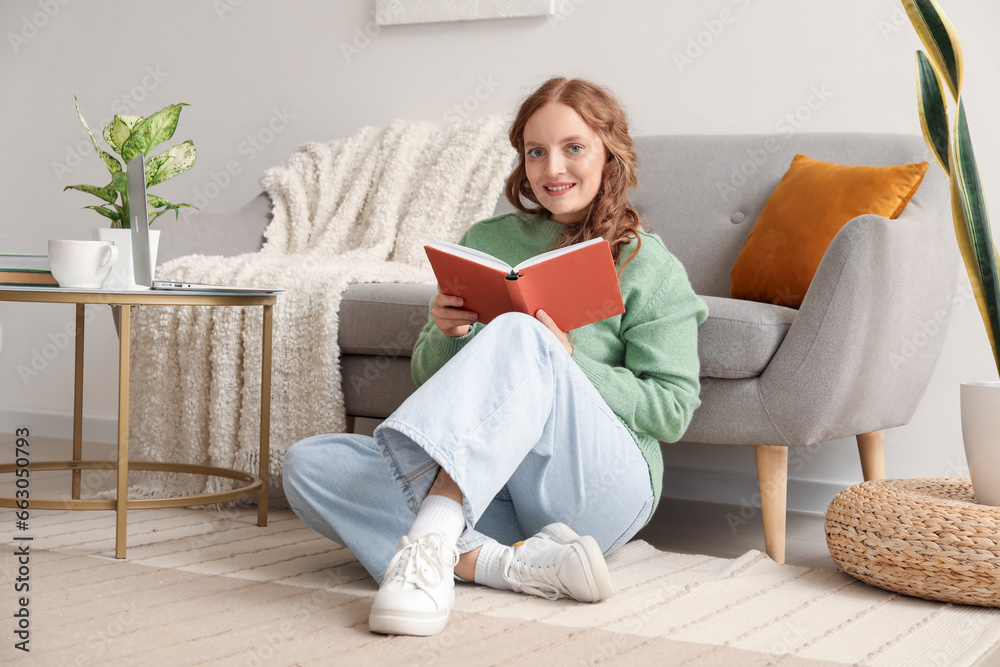 Beautiful redhead woman reading book at home