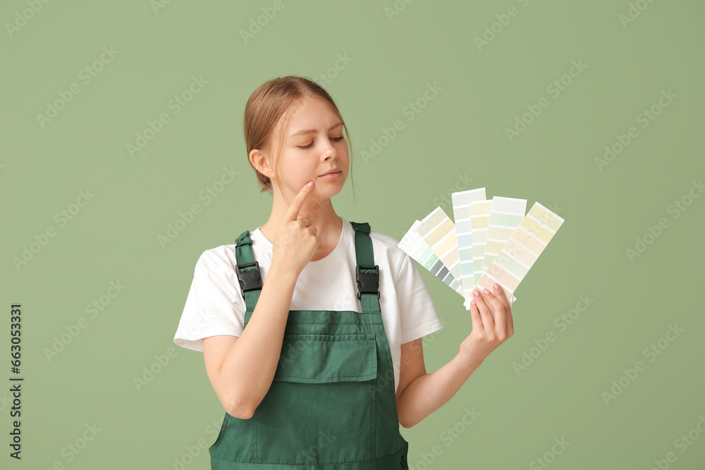 Thoughtful female decorator with color samples on green background