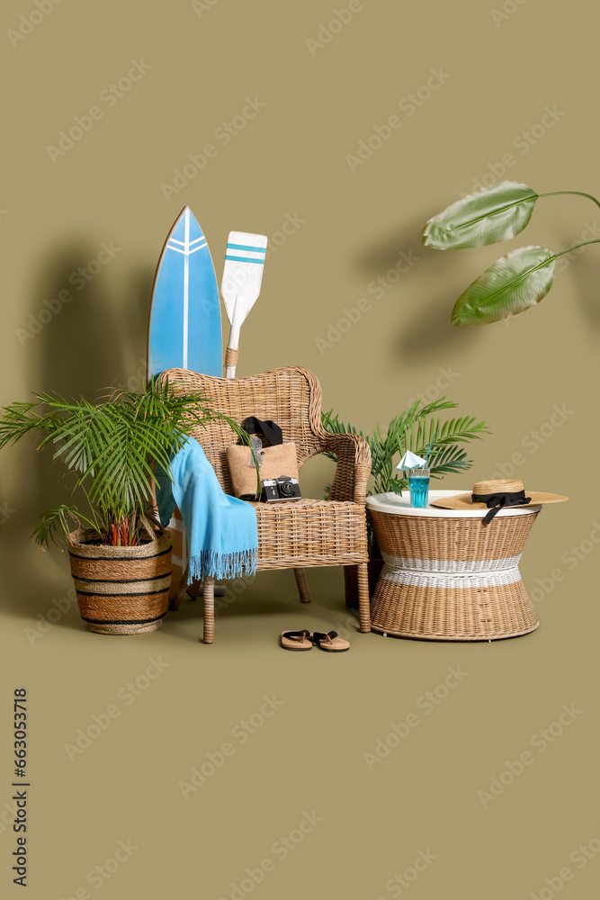 Chair, beach accessories and surfboard on green background