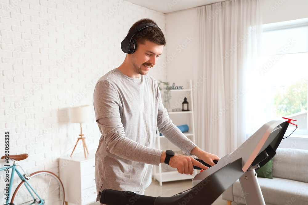 Sporty young man training on treadmill at home