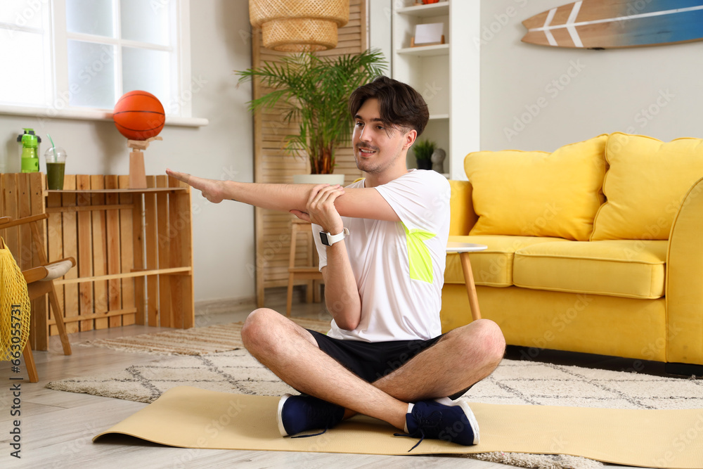 Sporty young man stretching at home