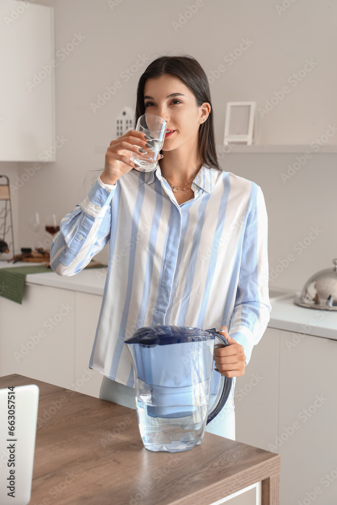 Young woman drinking filtered water in kitchen