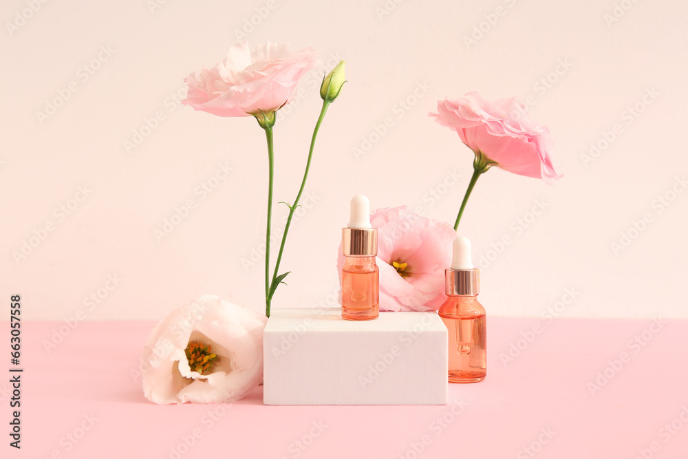 Composition with bottles of essential oil, plaster podium and beautiful eustoma flowers on pink background