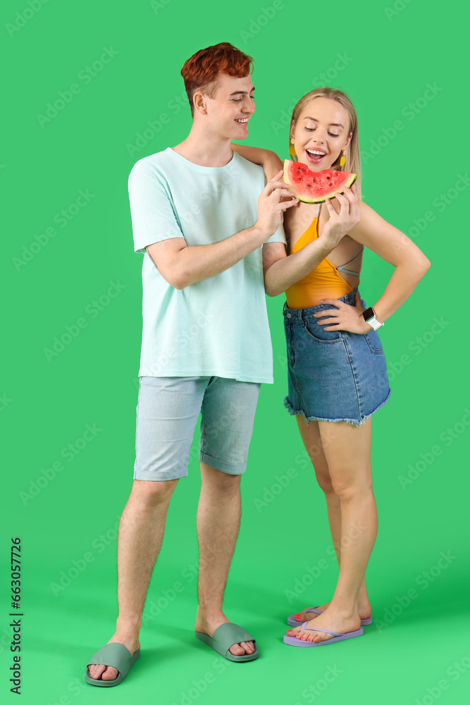 Young beautiful man and woman with slice of fresh watermelon on green background