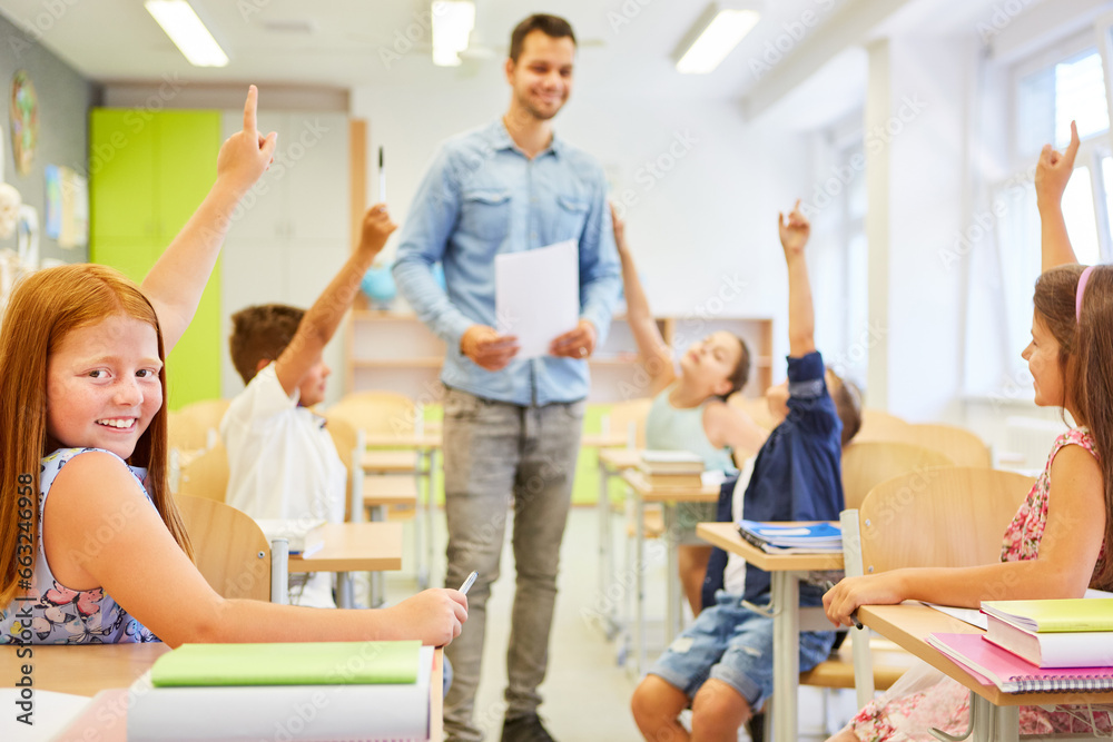 Teacher with kids sitting with hand raised in classroom