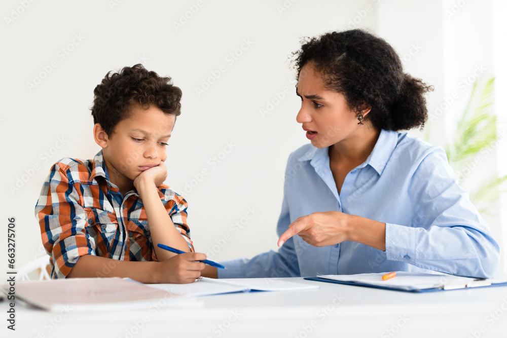 Teacher woman scolding student boy in modern classroom interior