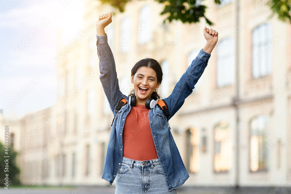 Cheerful indian young woman student raising hands up