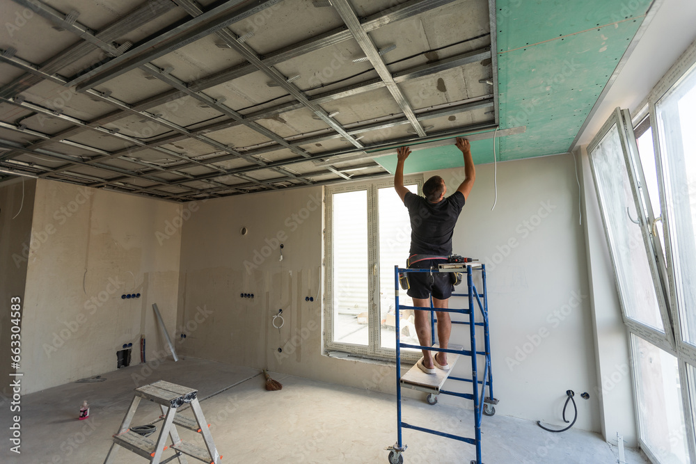 Two workers are mounted ceiling in the new flat