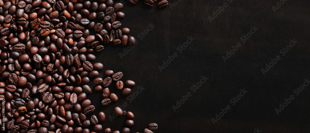 Roasted coffee beans on a wooden dark table, top view. Background of fragrant brown coffee beans scattered over the surface. copy space. Place for text