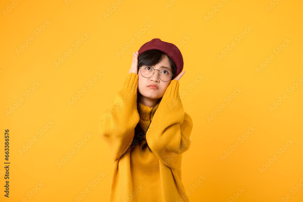 Stressed by noise. A woman, wearing a yellow sweater and red beret, tries to find peace amidst the chaos against a vibrant yellow backdrop.