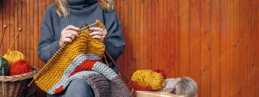 Woman knitting woolen warm clothing. Ball of wool in basket. Handmade yarn sweater