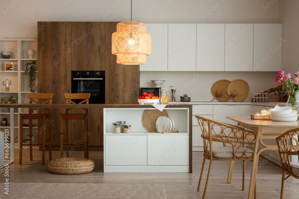 Interior of modern kitchen with dining table, island and glowing lamp