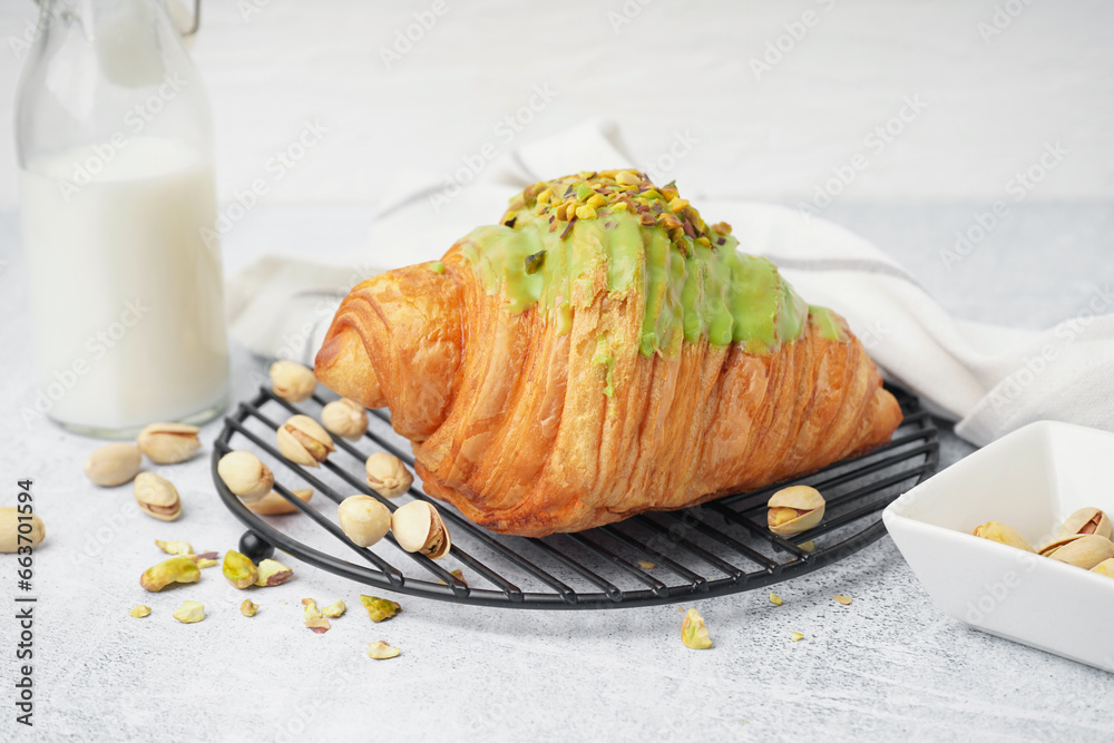 Grid with tasty croissant and pistachio nuts on white background