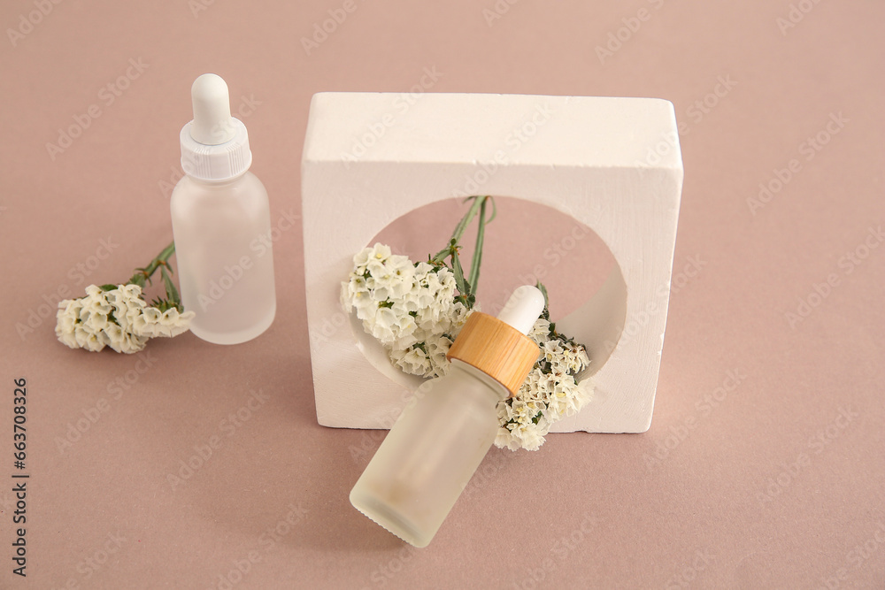 Composition with bottles of essential oil, plaster podium and beautiful flowers on beige background, closeup