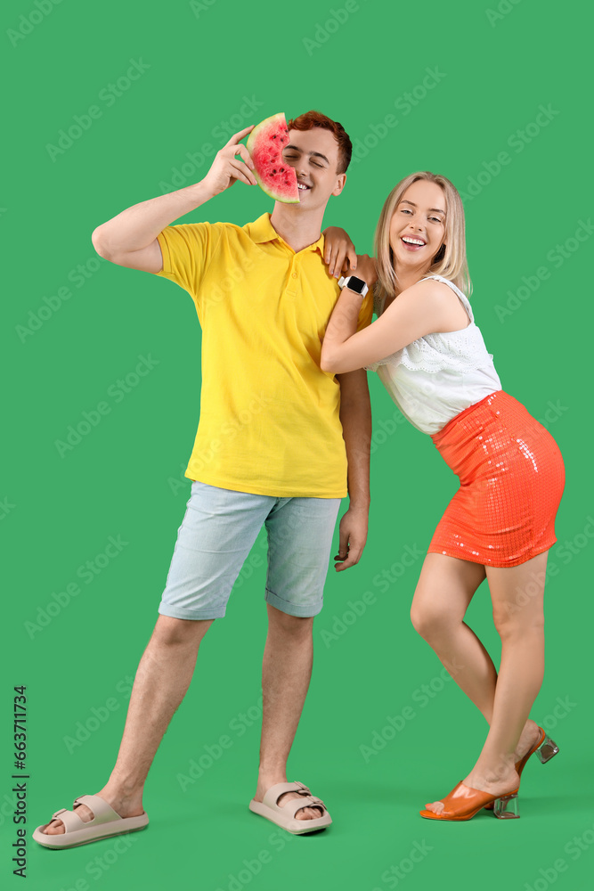 Young beautiful man and woman with slice of fresh watermelon on green background