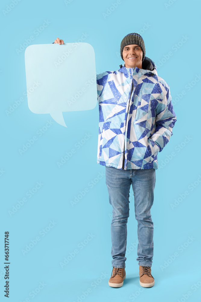 Young man in winter clothes with blank speech bubble on color background