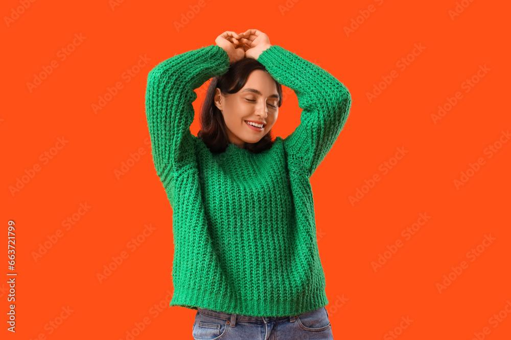 Young woman in green sweater on orange background