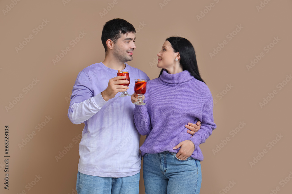 Young couple with glasses of mulled wine on color background