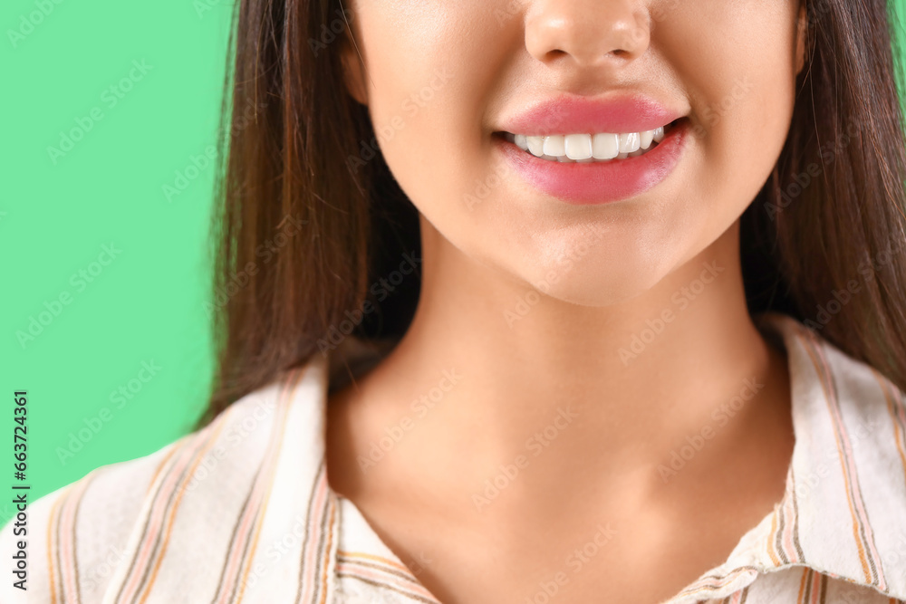 Smiling young woman with healthy teeth on green background, closeup