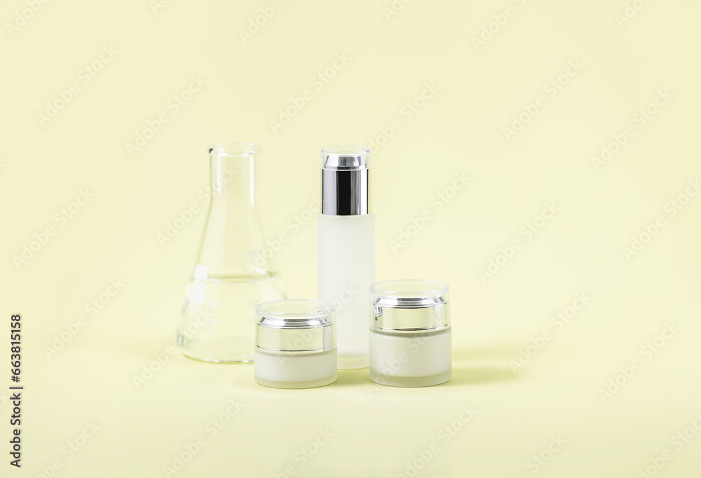 cosmetic containers and a laboratory flask on a yellow background