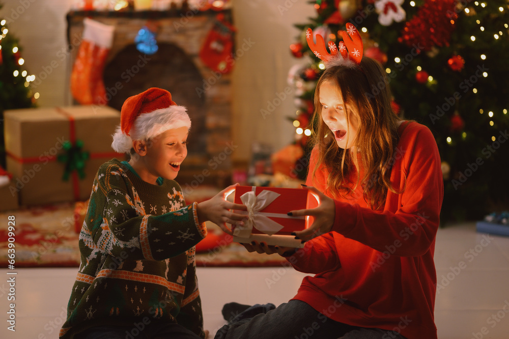 Cute girl and boy in Santa hats with red Christmas gift boxes. Celebration concept and people Merry Christmas happy holidays