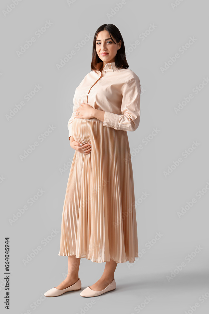 Young pregnant woman on light background