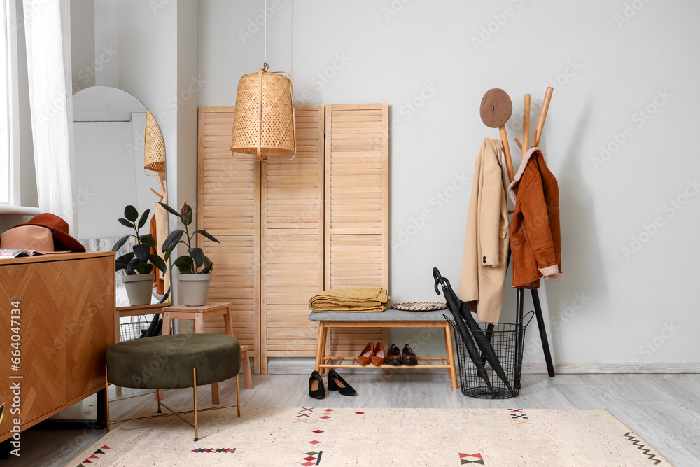 Interior of light living room with wooden cabinet, bench and mirror