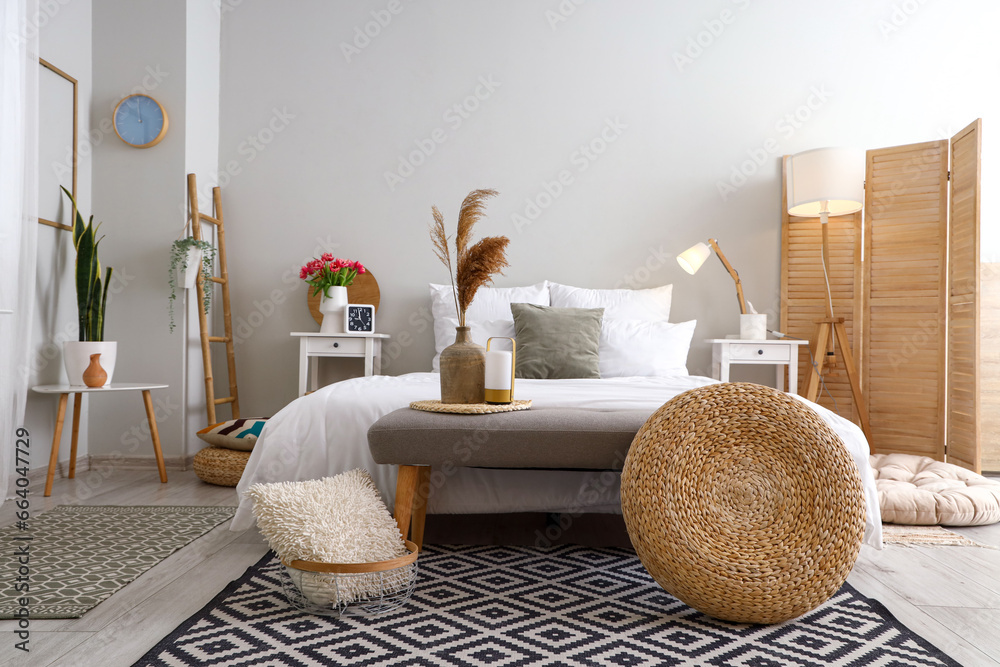 Interior of light bedroom with soft bench and tables