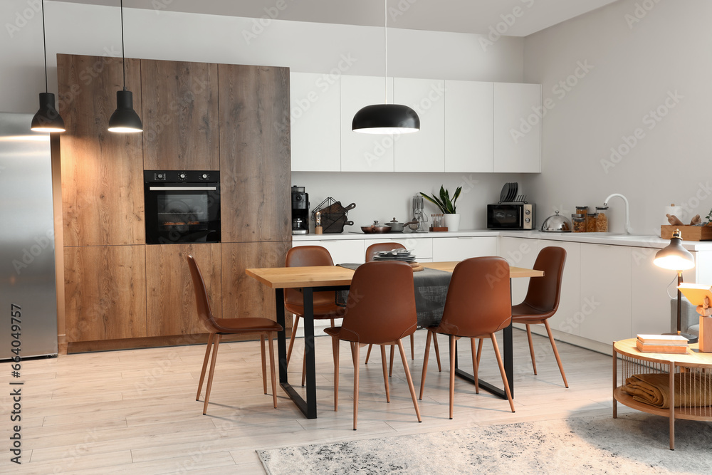 Interior of modern kitchen with dining table and glowing lamps