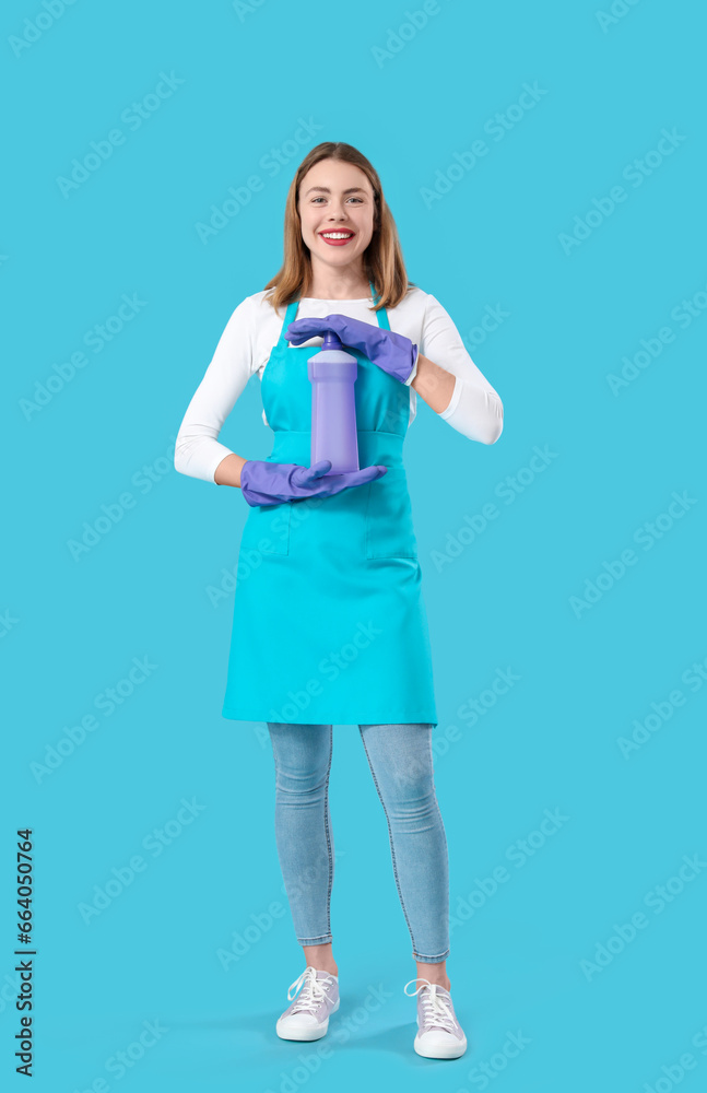 Young woman with bottle of detergent on blue background