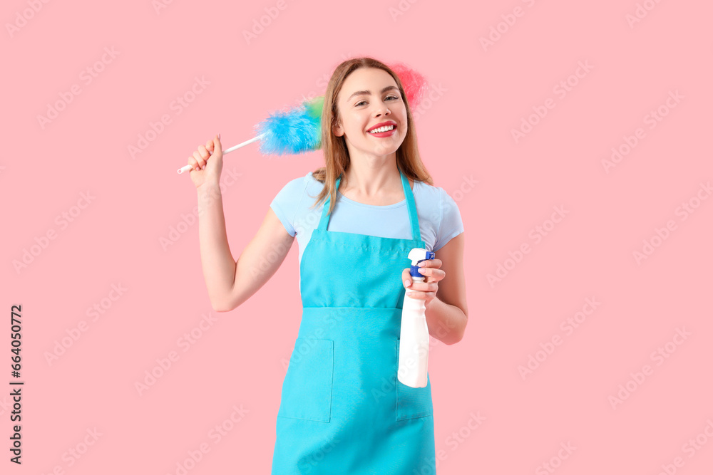 Young woman with bottle of detergent and pp-duster on pink background