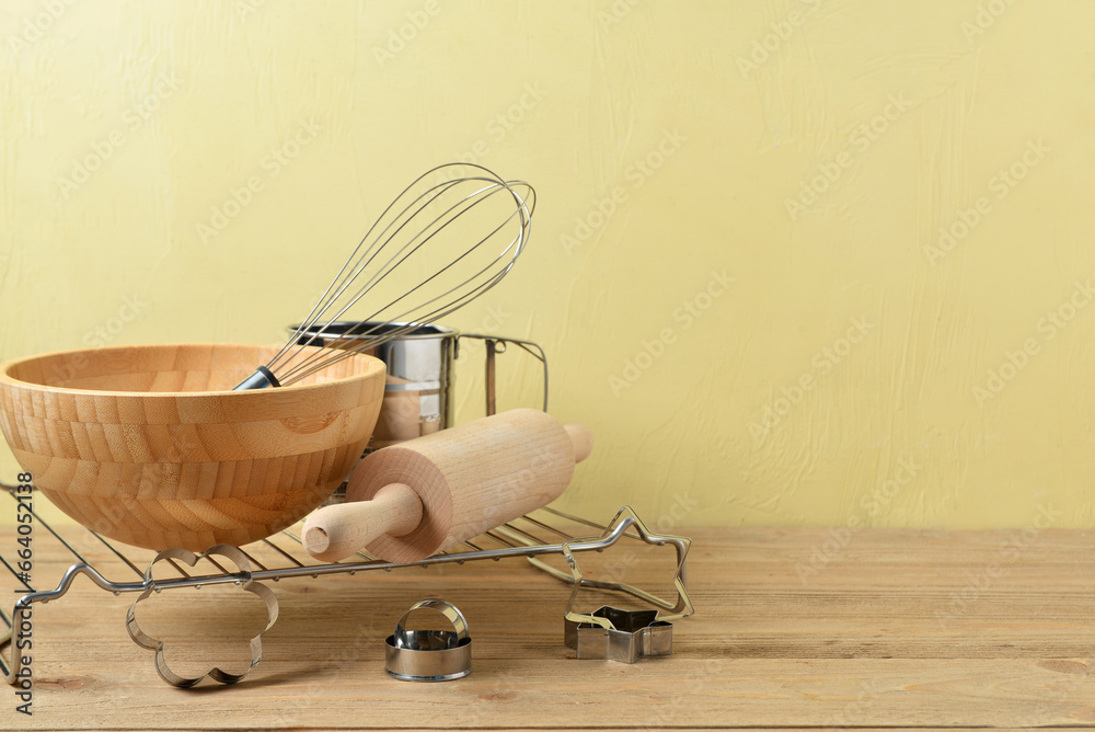 Set of baking utensils on wooden table near wall