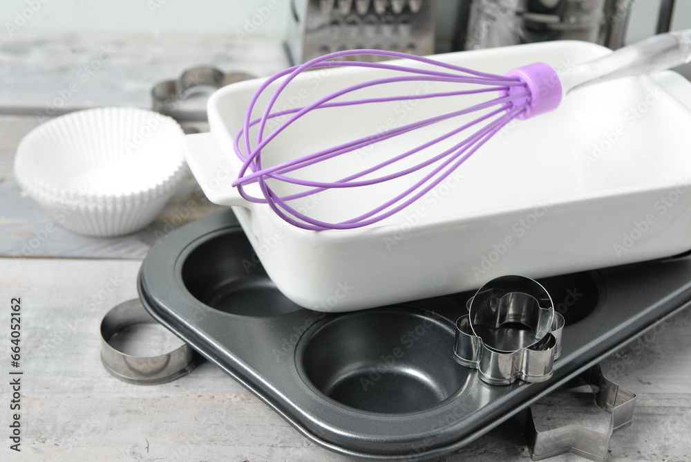 Set of kitchen utensils and baking dish on white wooden table