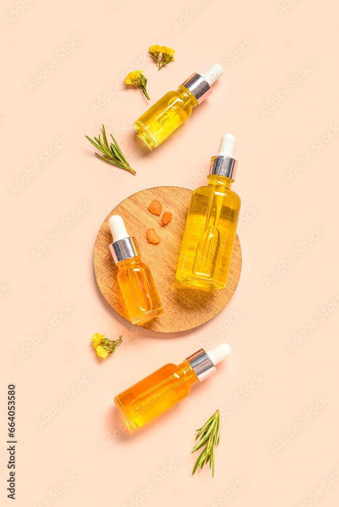 Wooden board with bottles of different healthy essential oils, herbs and flowers on pale orange background