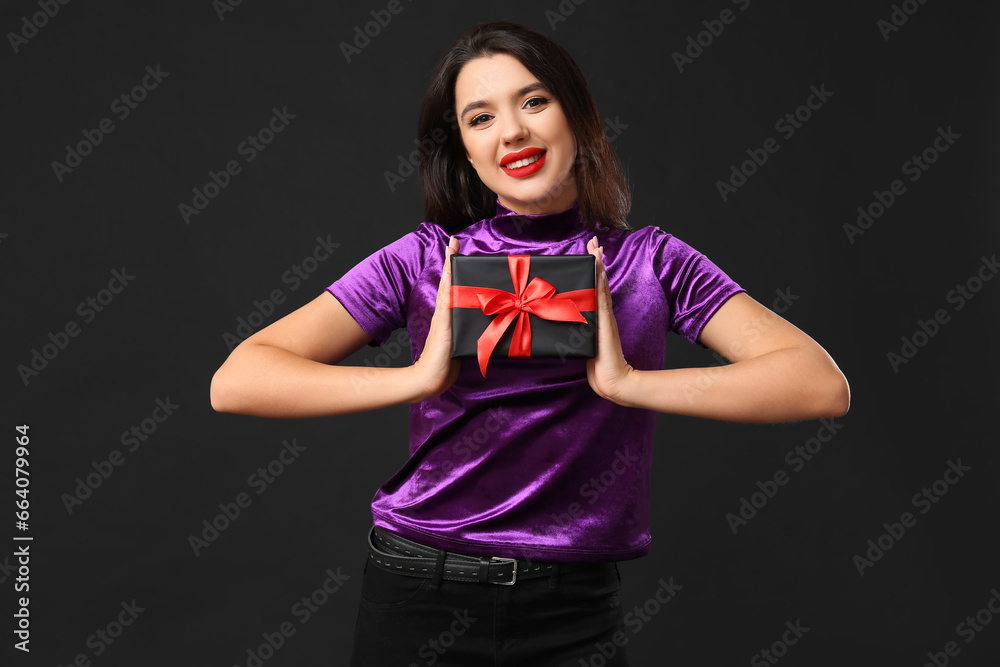 Beautiful woman with gift box on dark background. Black Friday sale