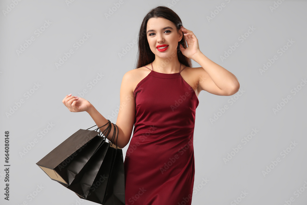 Beautiful woman with shopping bags on grey background. Black Friday sale