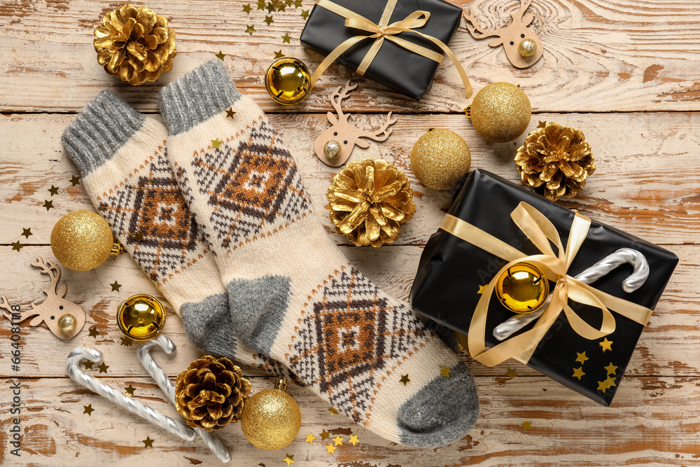 Warm socks with Christmas decor and gifts on white wooden background