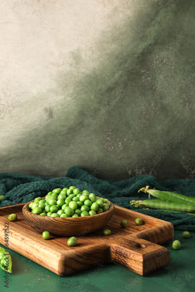 Bowl and wooden board with fresh green peas on color table