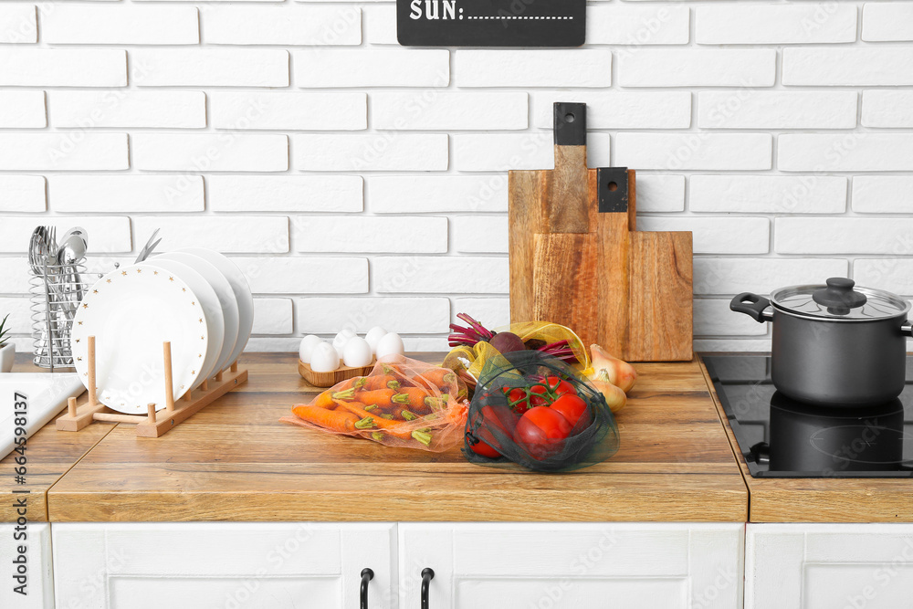 Eco bags with different fresh vegetables on counter in kitchen