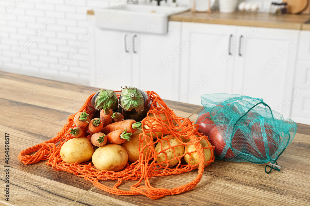 Eco bags with different ripe vegetables on counter in kitchen, closeup