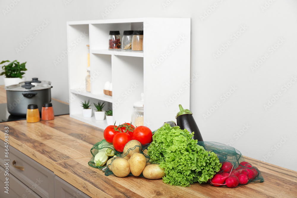 Eco bags with different fresh vegetables on counter in kitchen