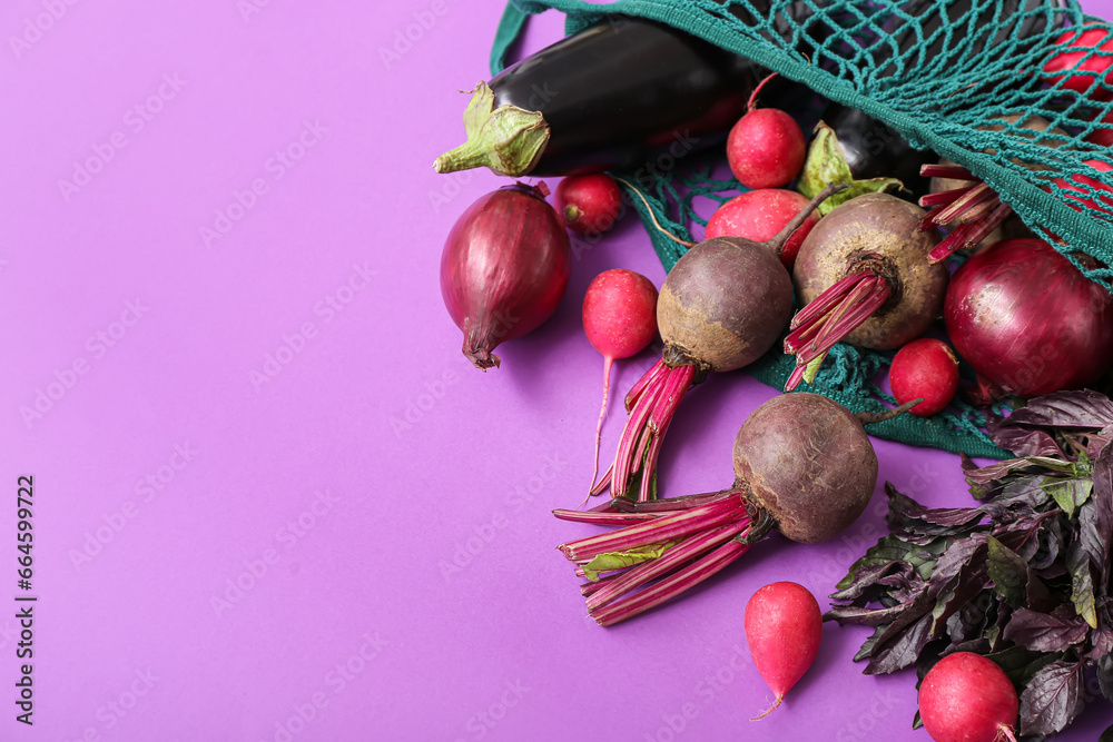 Mesh bag with different fresh vegetables on purple background, closeup