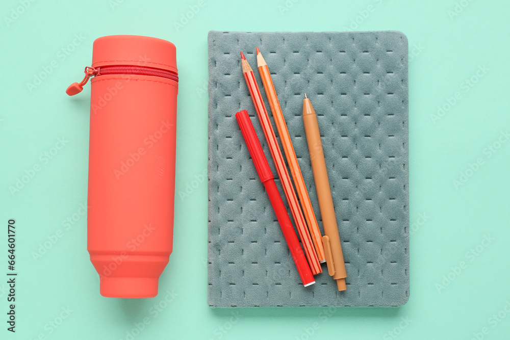 Case with pencils, pens and notebook on turquoise background