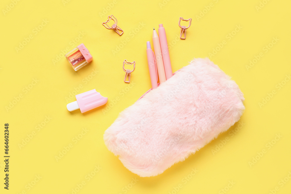 Pink pencil case with school stationery on yellow background